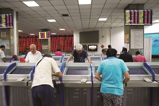 Investors look at computer screens showing stock information at a brokerage house in Shanghai. The worsening Sino-US trade war has battered Chinau2019s stocks and currency this year but that hasnu2019t stopped foreign investors rushing into the countryu2019s capital markets, which are increasingly opening up despite rising protectionism.