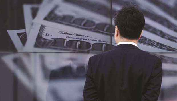 A businessman looks at a screen displaying a photo of  $100 bank notes in Tokyo. Not only does the US currencyu2019s climb tend to erode the profits of American multinationals, but it also raises the costs of foreign corporations with trillions of dollar-denominated debt. The pressure from greenback strength on other economies could even encourage those countries to join a US attempt to weaken it.