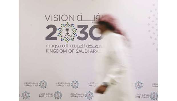 A Saudi man walks past the logo of Vision 2030 in Jeddah (file). With one of the worldu2019s lowest debt levels, Saudi Arabia has been one of the biggest issuers in emerging markets after a drop in oil prices prompted the  government to cut spending and seek alternative sources of funding.