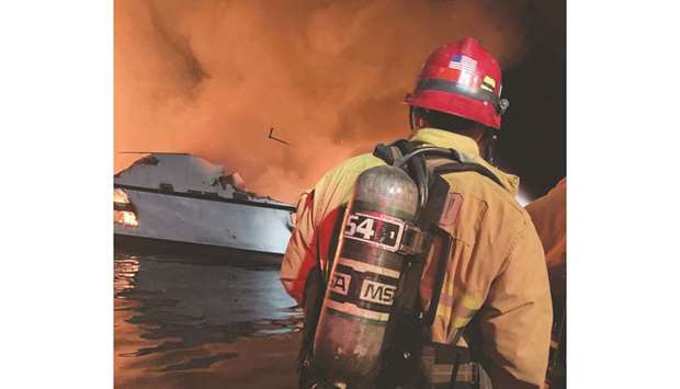 This photo released by the Ventura County Fire Department shows a firefighter near the boat on fire, off the coast of Santa Cruz Island, California.