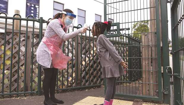 A member of staff takes a childu2019s temperature at a school in London. The reopening of schools in Britain has taken on greater political and economic significance because the country has been hit by the pandemic more than anywhere else in Europe.