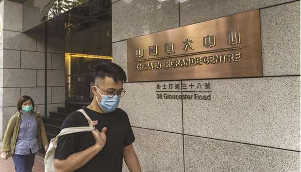 Pedestrians walk past the China Evergrande Centre in Hong Kong. The developeru2019s borrowings, or interest-bearing debt, fell to a five-year low as of June 30. But its overall liabilities rose to a near-record $305bn, thanks mainly to swelling bills to suppliers.