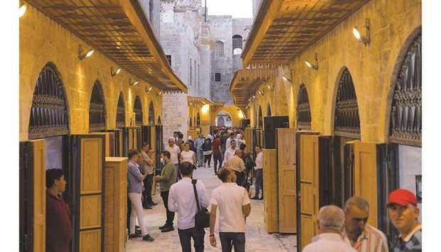 People walk about in the reopened u201cSouq Khan al-Hariru201d in Syriau2019s northern city of Aleppo after reconstruction efforts in the wake of years of conflict.