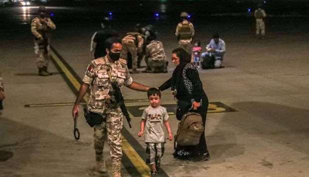 A member of the Qatar Air force walks next to a boy evacuated from Afghanistan, at Al-Udeid airbase in Doha. File photo