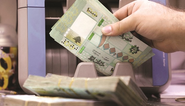 A man counts Lebanese pound banknotes at a currency exchange shop in Beirut. The pound plunged to 38,600 against the greenback on Monday, according to websites monitoring the exchange rate, a record low for the beleaguered currency.