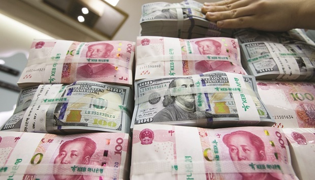 An employee arranges bundles of US dollar banknotes and Chinese yuan in an arranged photograph in Seoul. The yuan is set to slide past 7 per dollar with scarcely a murmur as a range of metrics show the currency would still be relatively expensive against its non-dollar peers, according to analysts.