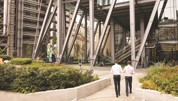 Workers pass near the Lloyds of London building and The Leadenhall Building. Londonu2019s investment bankers have long grumbled that the regionu2019s bonus cap crimped their pay in high times. Its demise arrives in a year when few expect the change to unleash bumper payouts.