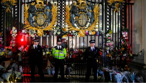Police officers stand guard as flowers are laid at a gate of Buckingham Palace after Queen Elizabeth, Britain's longest-reigning monarch and the nation's figurehead for seven decades, died aged 96, in London, Britain September 8, 2022.