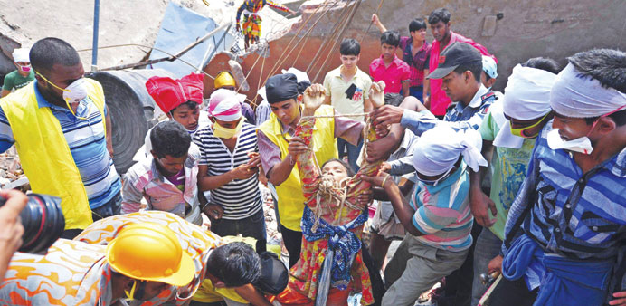 Bangladeshi firefighters help a survivor pulled from the debris.