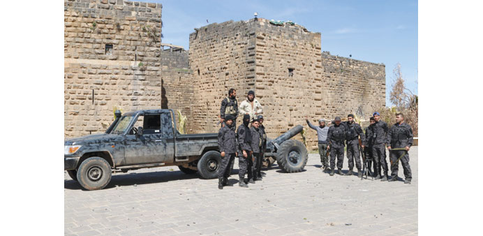 Rebel fighters pose yesterday in front of the ancient citadel of Bosra al-Sham after they took control of the area.