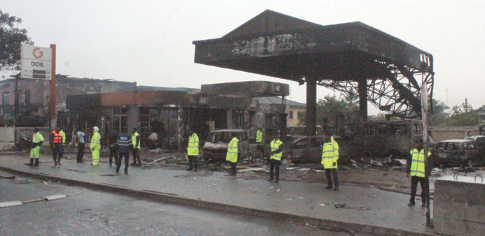 Police officers stand guard as rescuers work on the site where at least 90 people were killed in a petrol station fire in Accra.