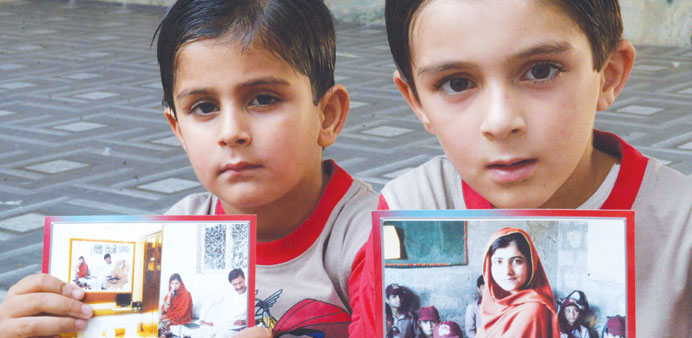 Nephews of education activist Malala Yousafzai holding up her photograph at home in Mingora yesterday.