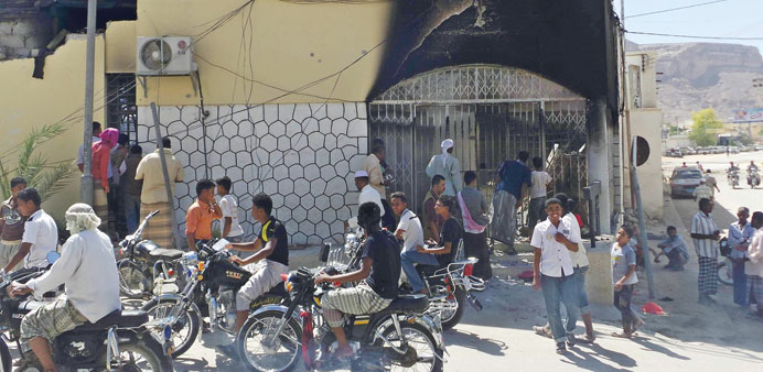 People gather outside a damaged bank after the raid by militants in Seiyun yesterday.