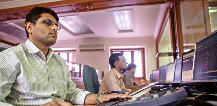 Employees work at their desks in a brokerage in Mumbai. Sensex touched a record high of 21,483.74 points on Monday.