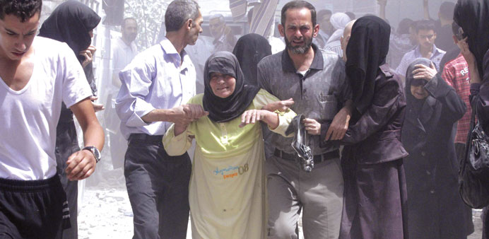 People assist an old woman at the site of a reported air strike by regime forces yesterday in Duma, near Damascus.