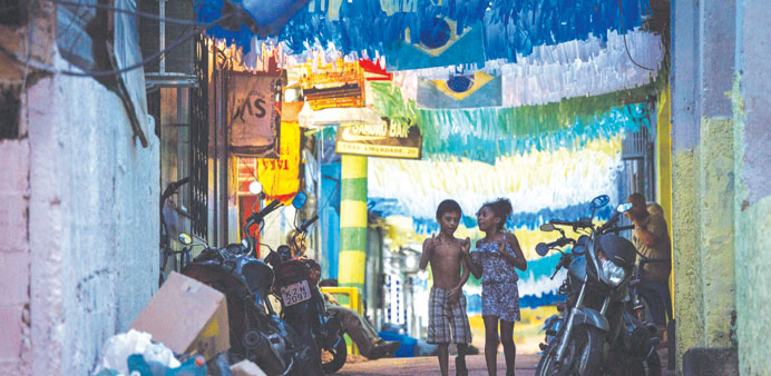 Two children walking along a street decorated in the Brazilian national colours in Rocinha shantytown (favela) in Rio de Janeiro.